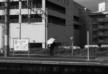 플랫폼에 양산을 쓰고 서있는 사람